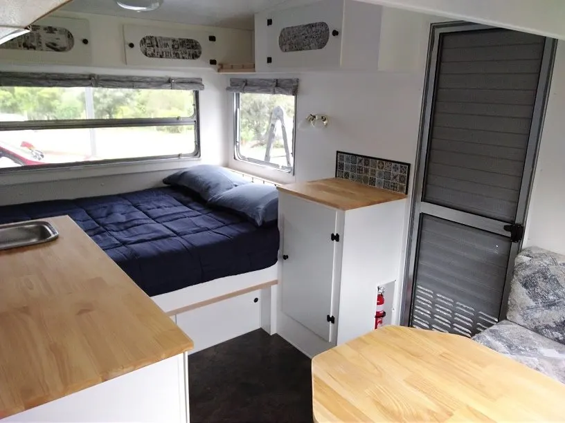 Interior of vintage caravan renovation showing door, storage cabinet and double bed.