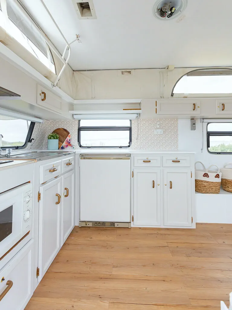 White kitchen cabinets inside a renovated vintage caravan