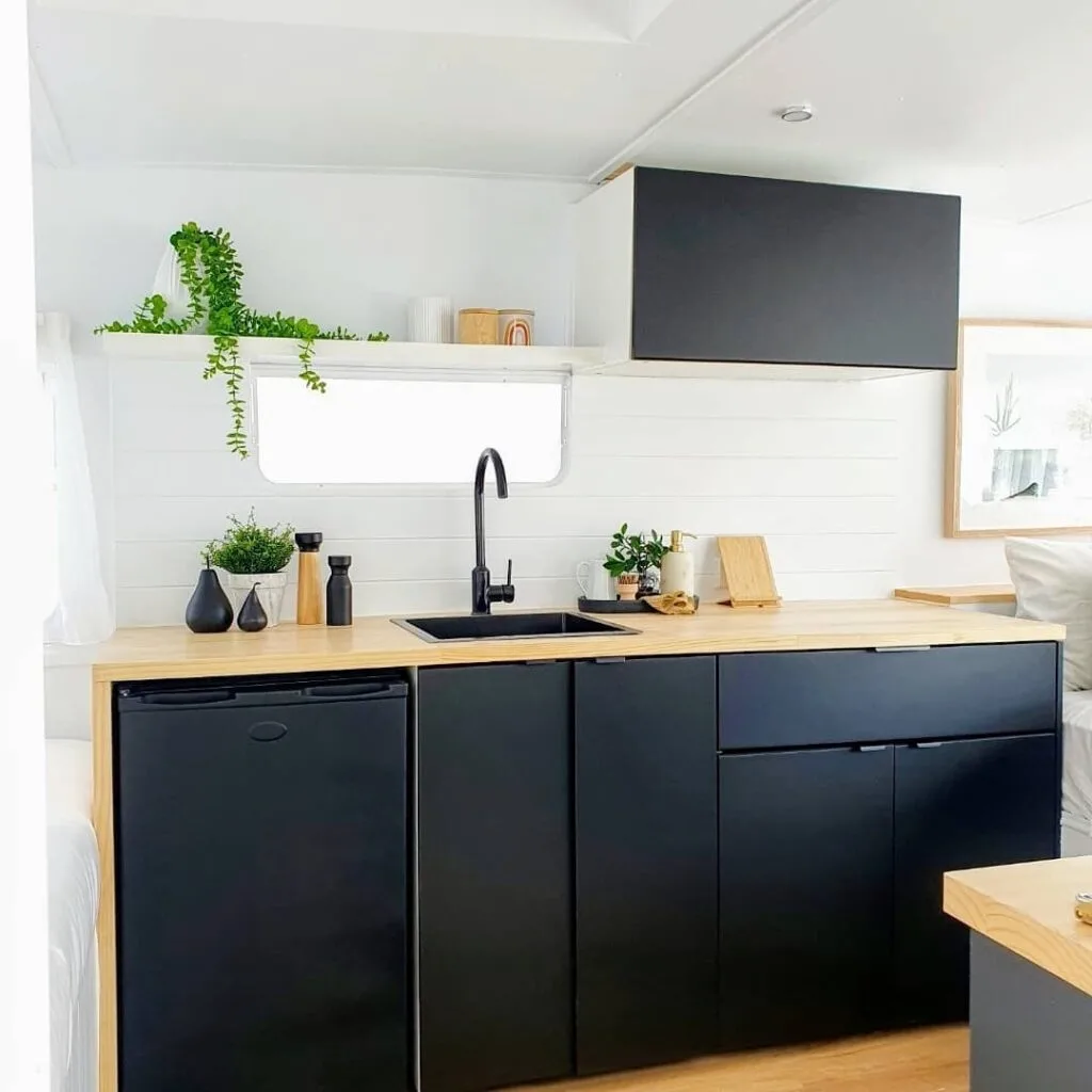 Dark blue cabinets and wooden countertop in a renovated caravan.