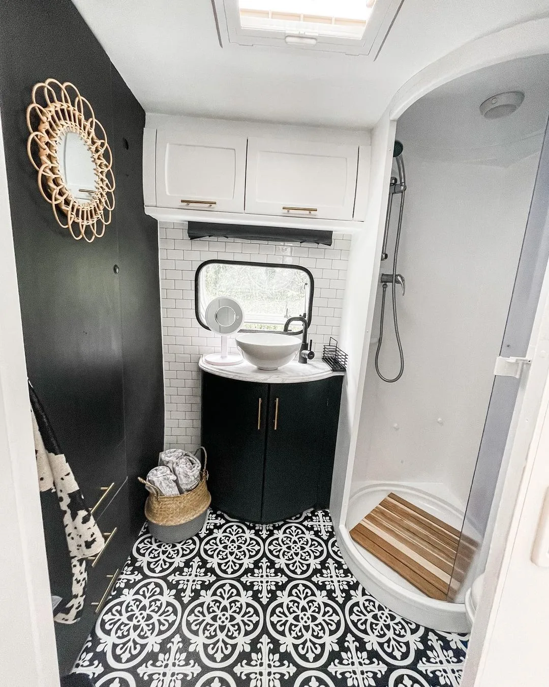 Caravan bathroom with black accent wall and black and white floor tiles.