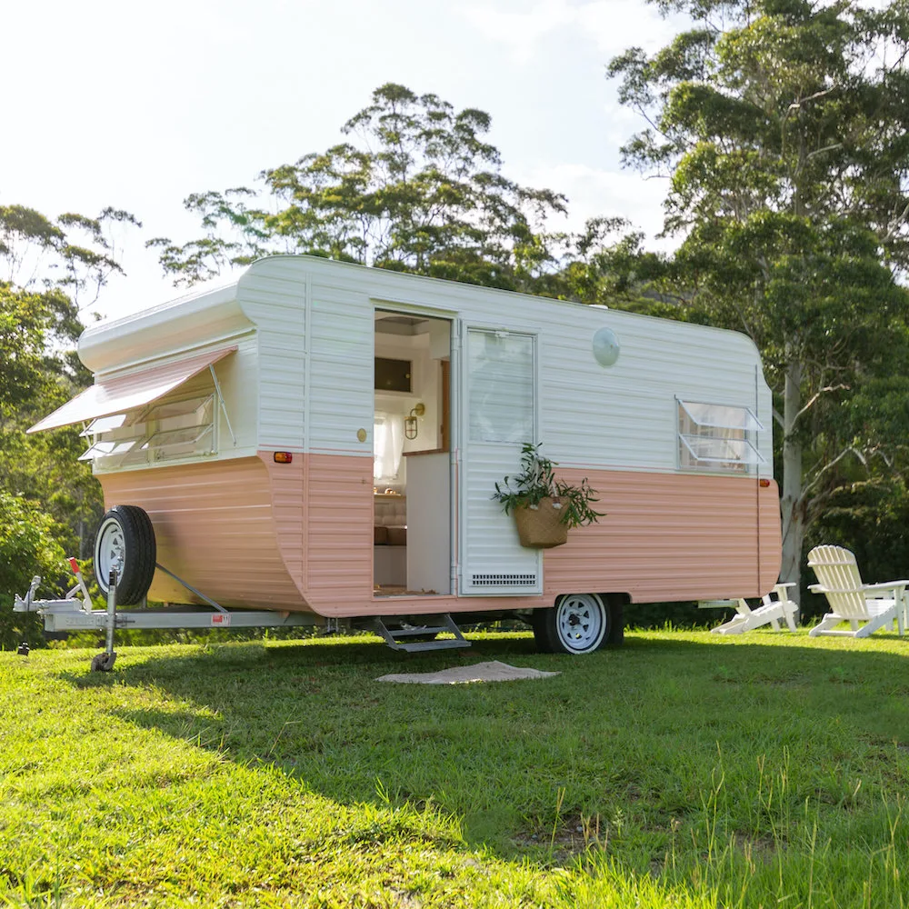 Exterior of a renovated caravan with pink and white body paint.