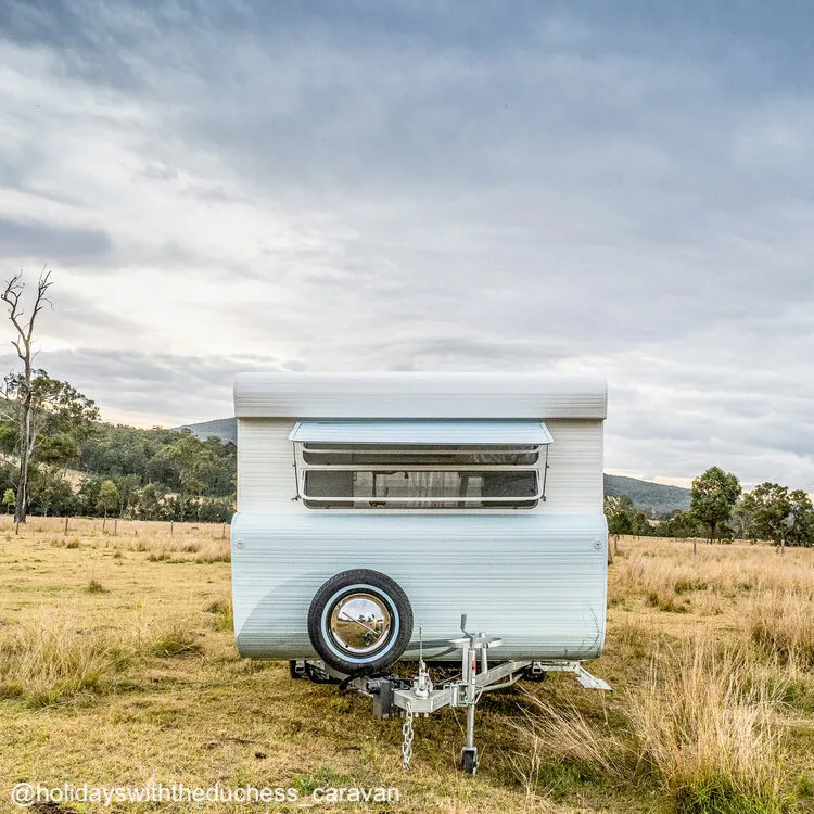 Renovated white and pale blue 1974 Viscount Supreme caravan sitting in a field.