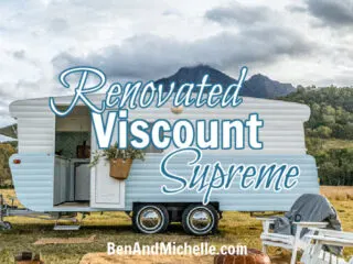 Renovated blue and white vintage caravan in a field with white lawn chairs arranged in front with text that reads: Renovated Viscount Supreme.
